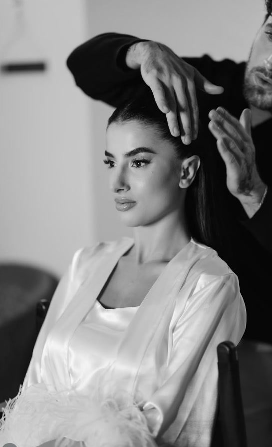 Noiva de robe de cetim sendo penteada antes da cerimônia, em preto e branco