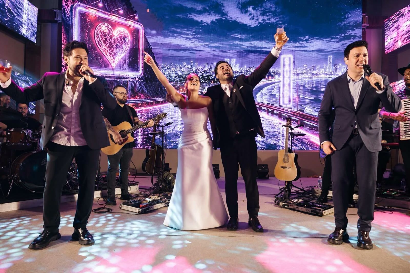 Noivos comemorando no palco com João Bosco e Vinícius e a banda